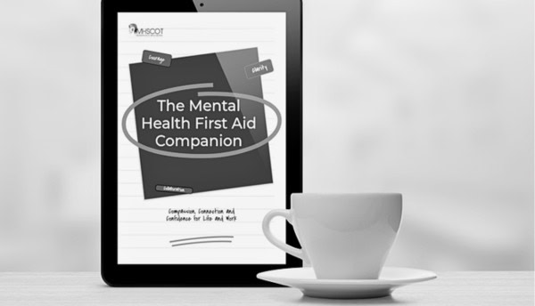 Digital tablet displaying "The Mental Health First Aid Companion" with a coffee cup nearby.